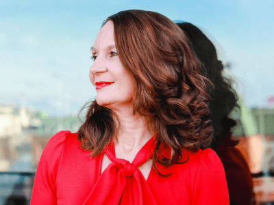 Martina Schuster steht vor einer Glaswand und schaut nach links